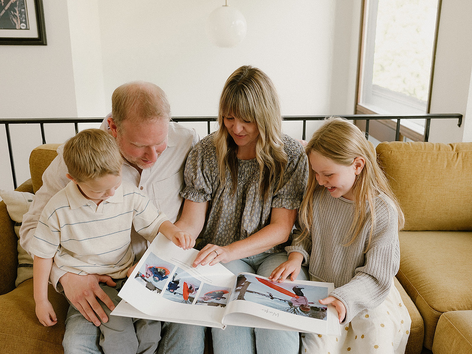 Two parents sit with two children looking through a family yearbook.