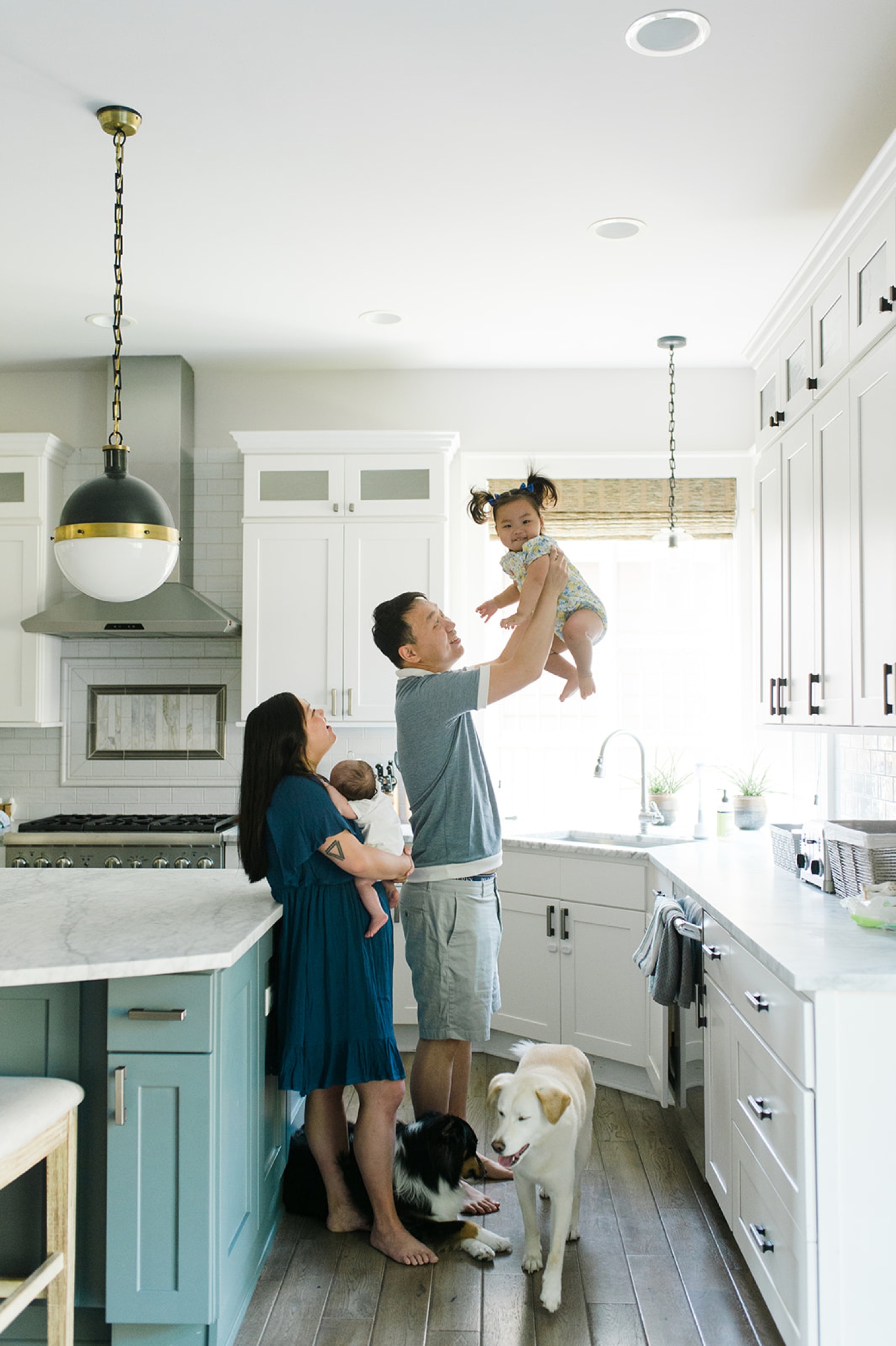 A mother and father hold their baby in a kitchen in a lifestyle photoshoot at their house.