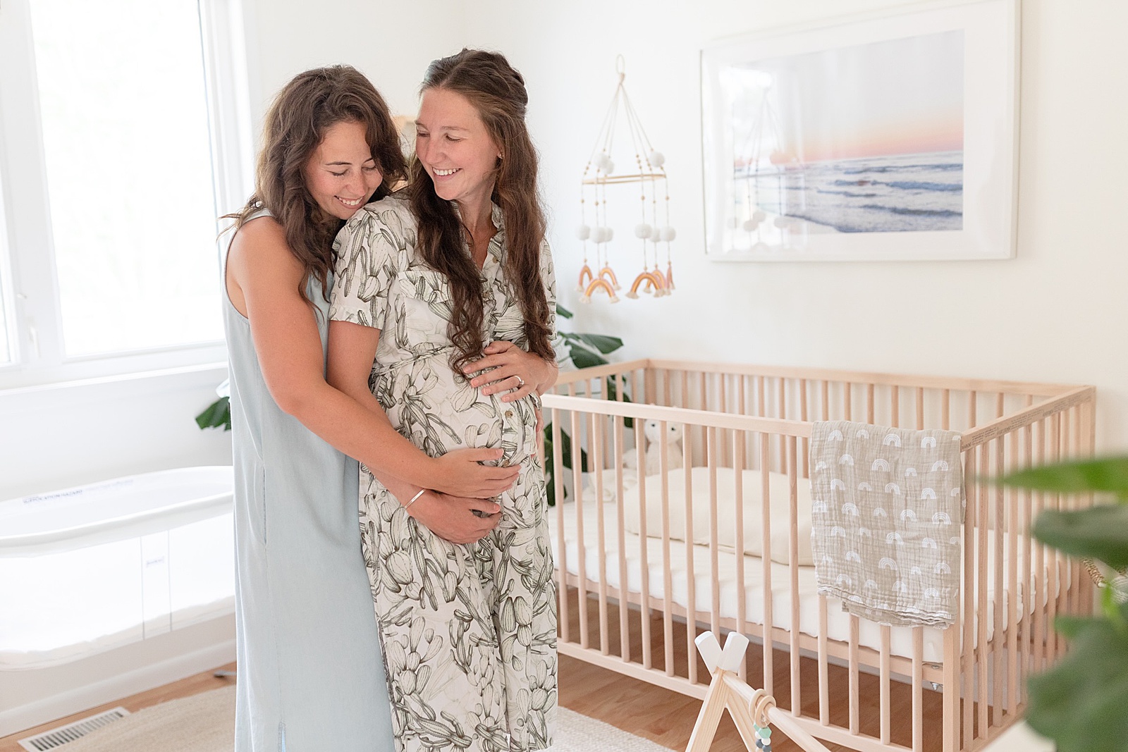 Two moms model beside a crib for a photo for their digital memory book.