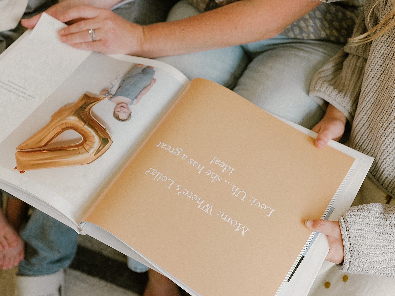 A mother and child look through a photo album created on the Baby Notebook app.