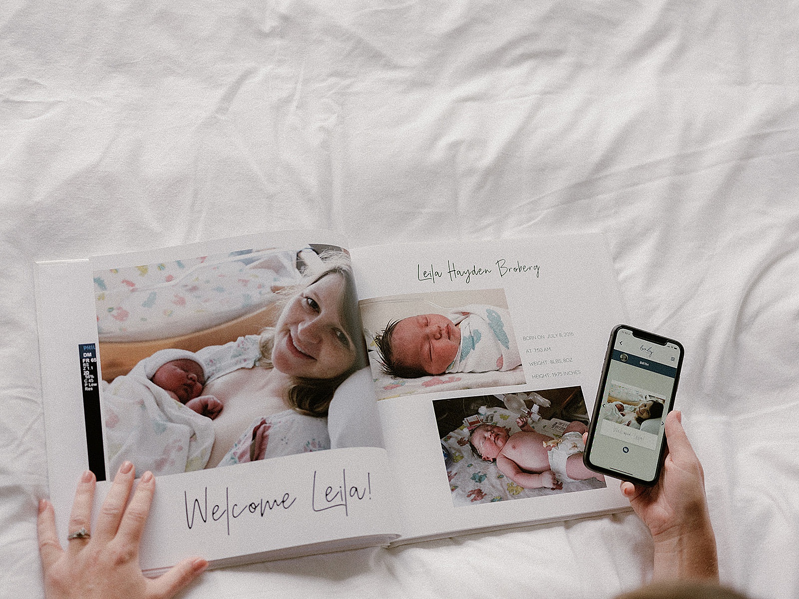 A woman holds a phone with a digital baby book app next to a printed baby book.