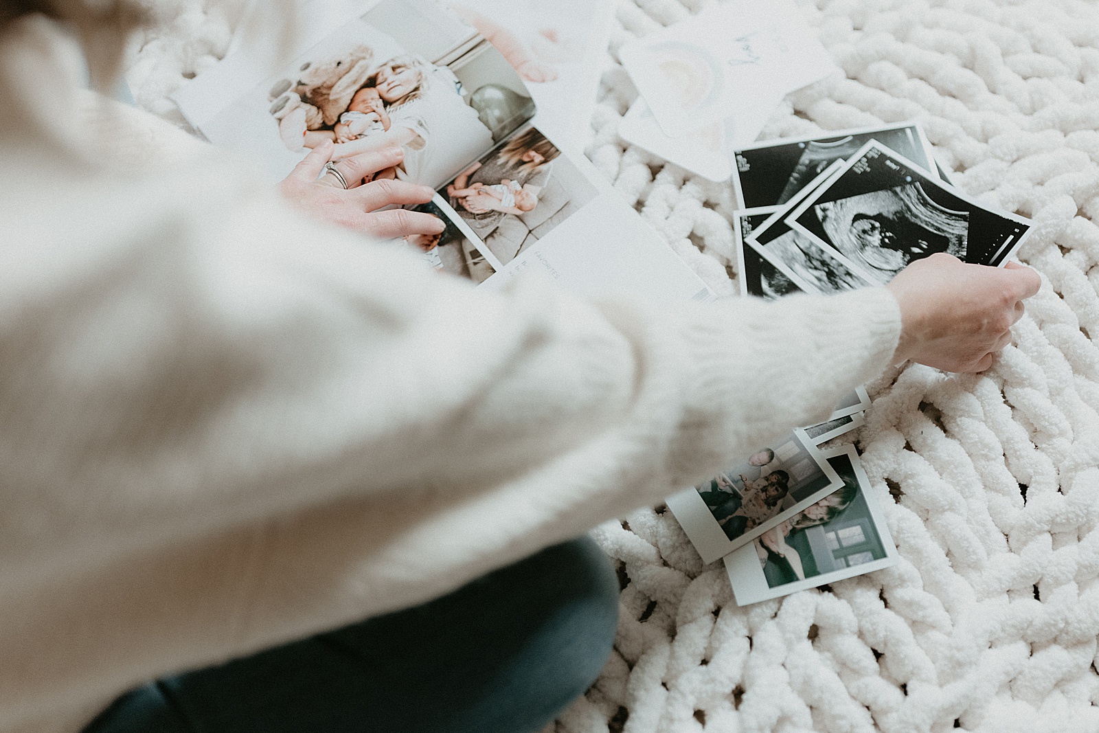 A woman sifts through ultrasound images next to a custom baby book.