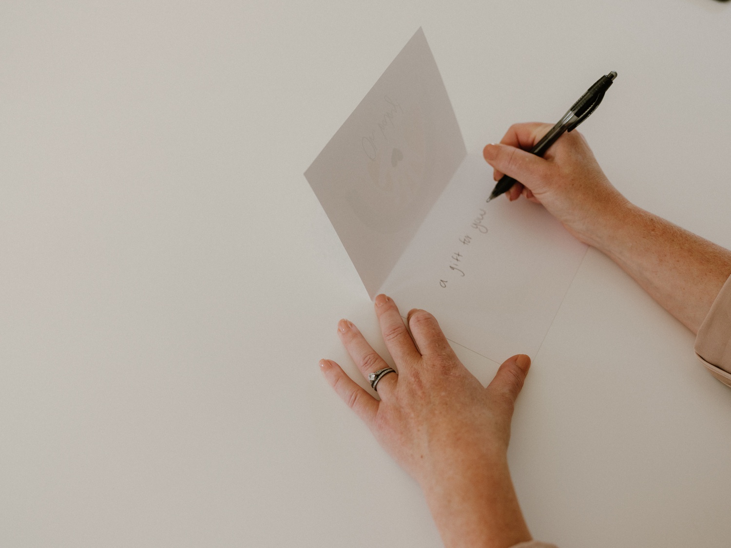 A woman writes a message inside a baby shower card.