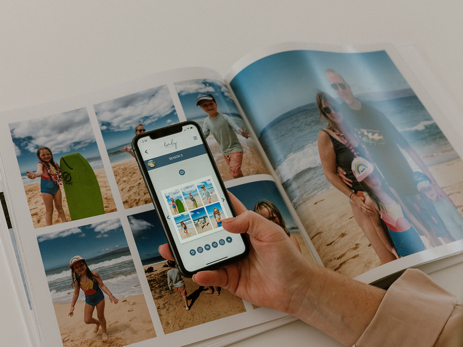 A woman shows a phone app beside a custom memory book.