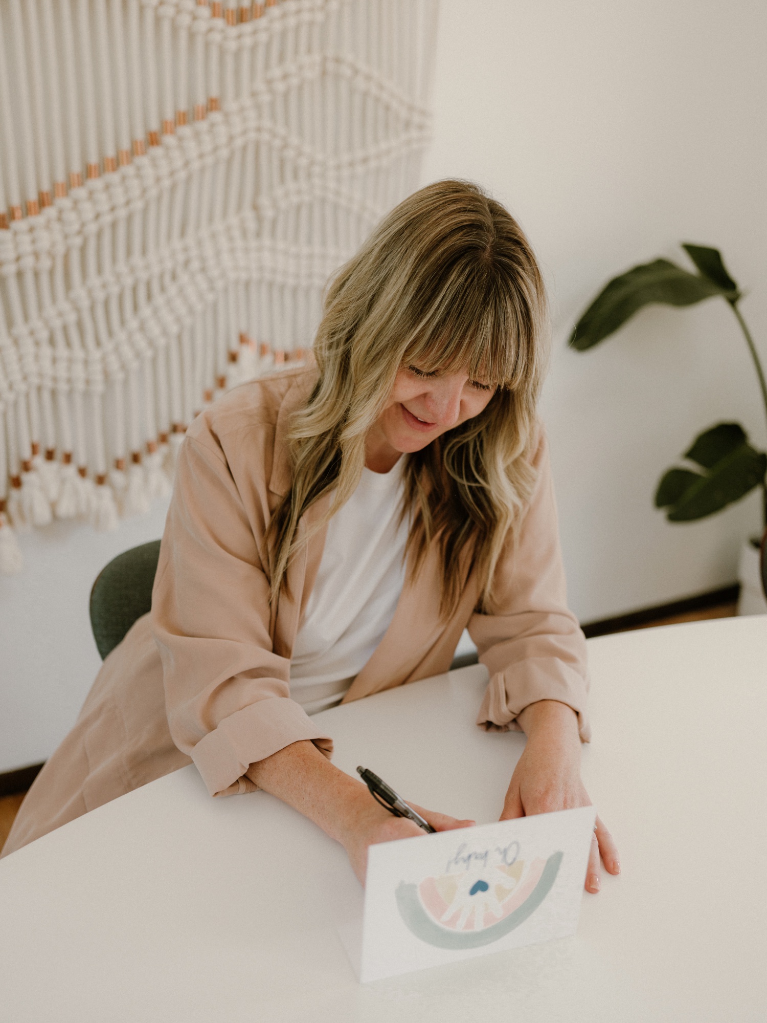 A woman sits at a table and writes out a list of baby shower gift ideas.