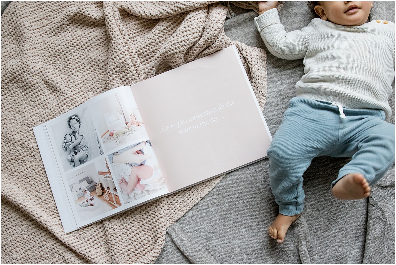 A baby lays beside a custom baby book made with a memory book app.