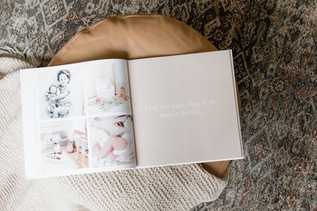 A baby book made with a memory book app sits open on a footstool.