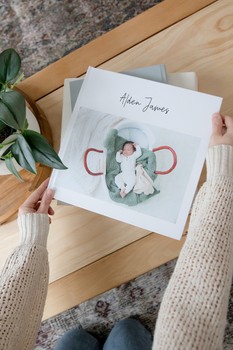 A woman sets a custom baby book on a coffee table.