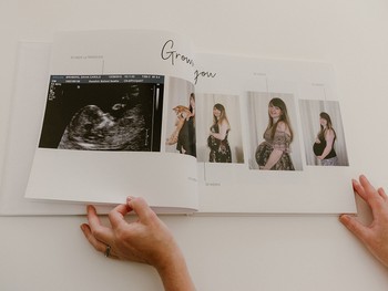 A woman flips through maternity photos in a modern baby book.