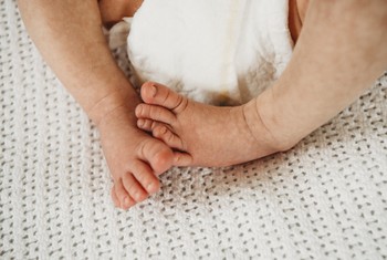 A baby touches his toes during a newborn photography session.