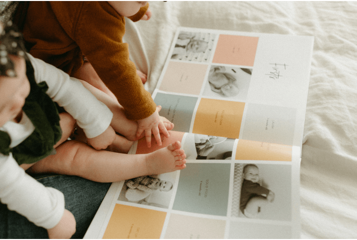 Twin baby hands and feet on modern baby book that is open in front of them
