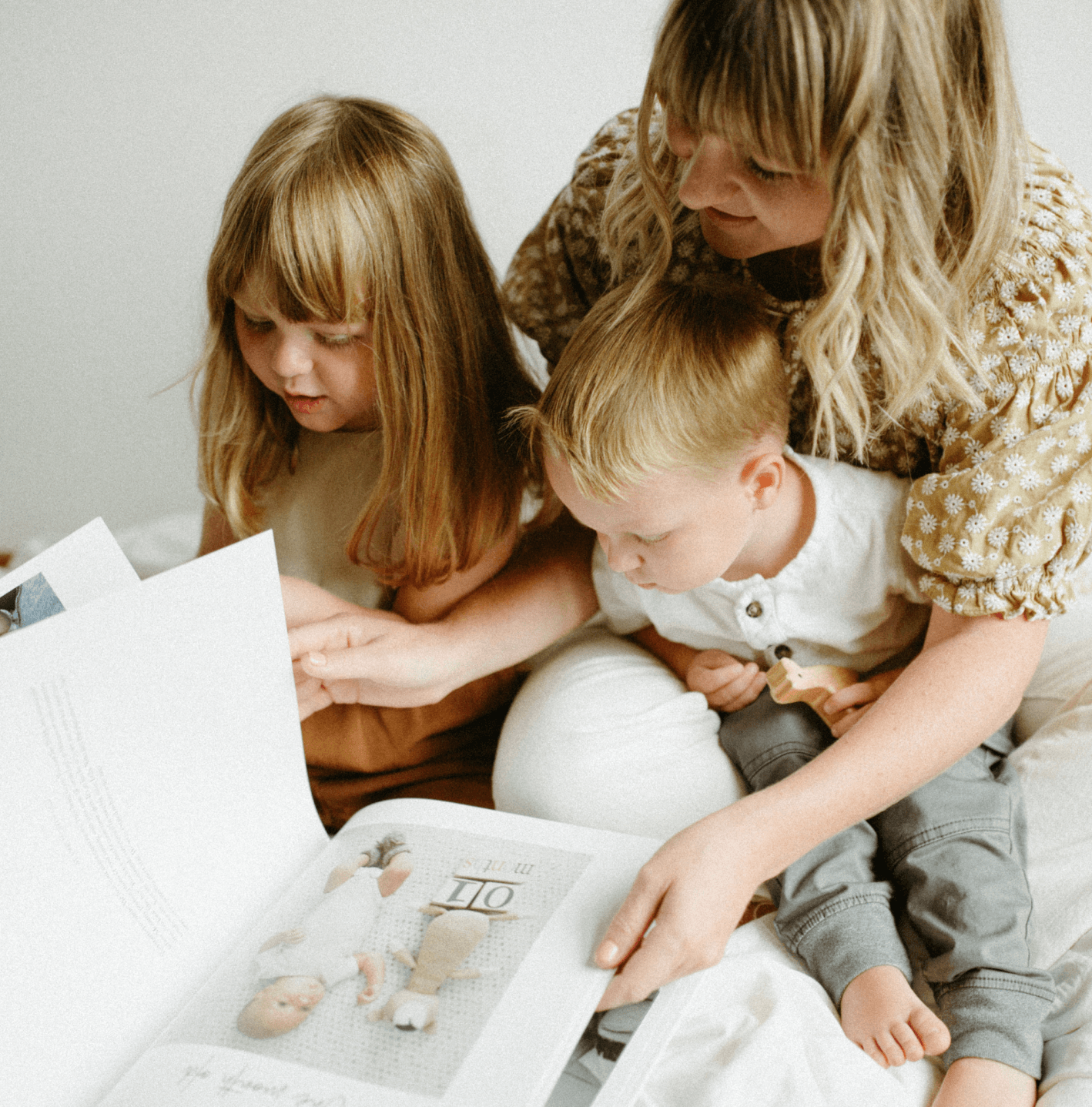 A mom and two toddlers flipping through a modern baby book
