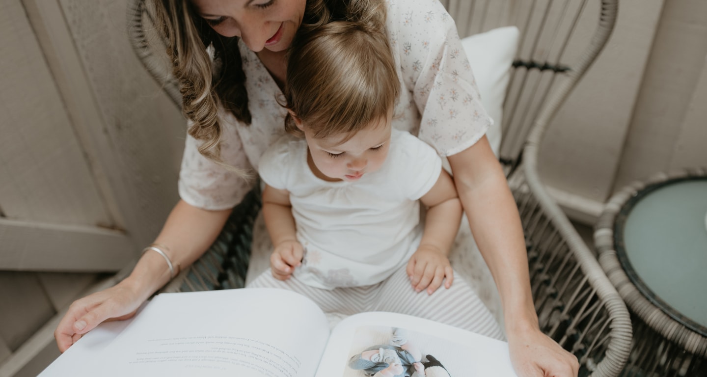 Mom with her toddler on her lap looking at a modern baby book